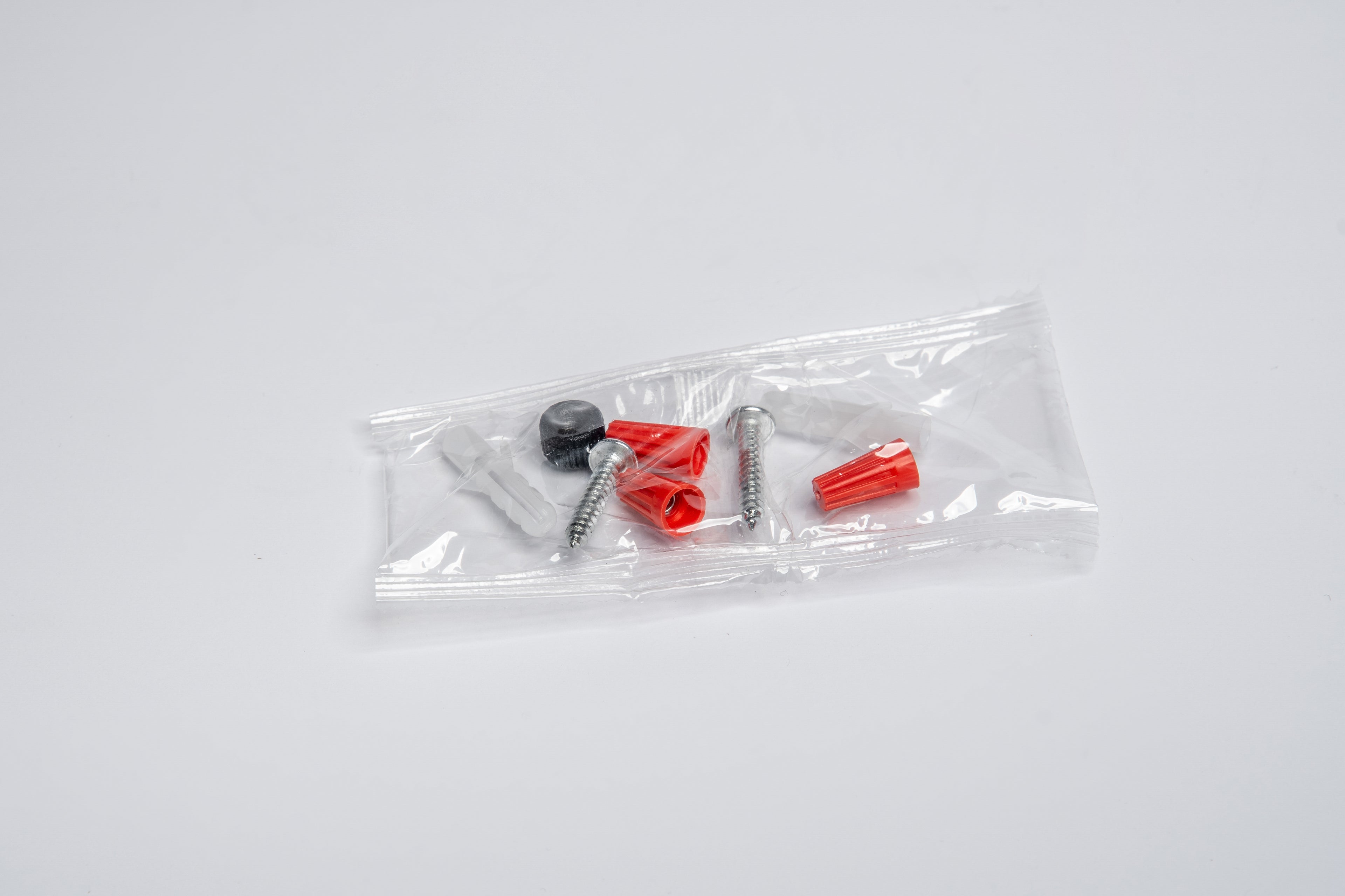 Packaged screws with red and black heads on a white background